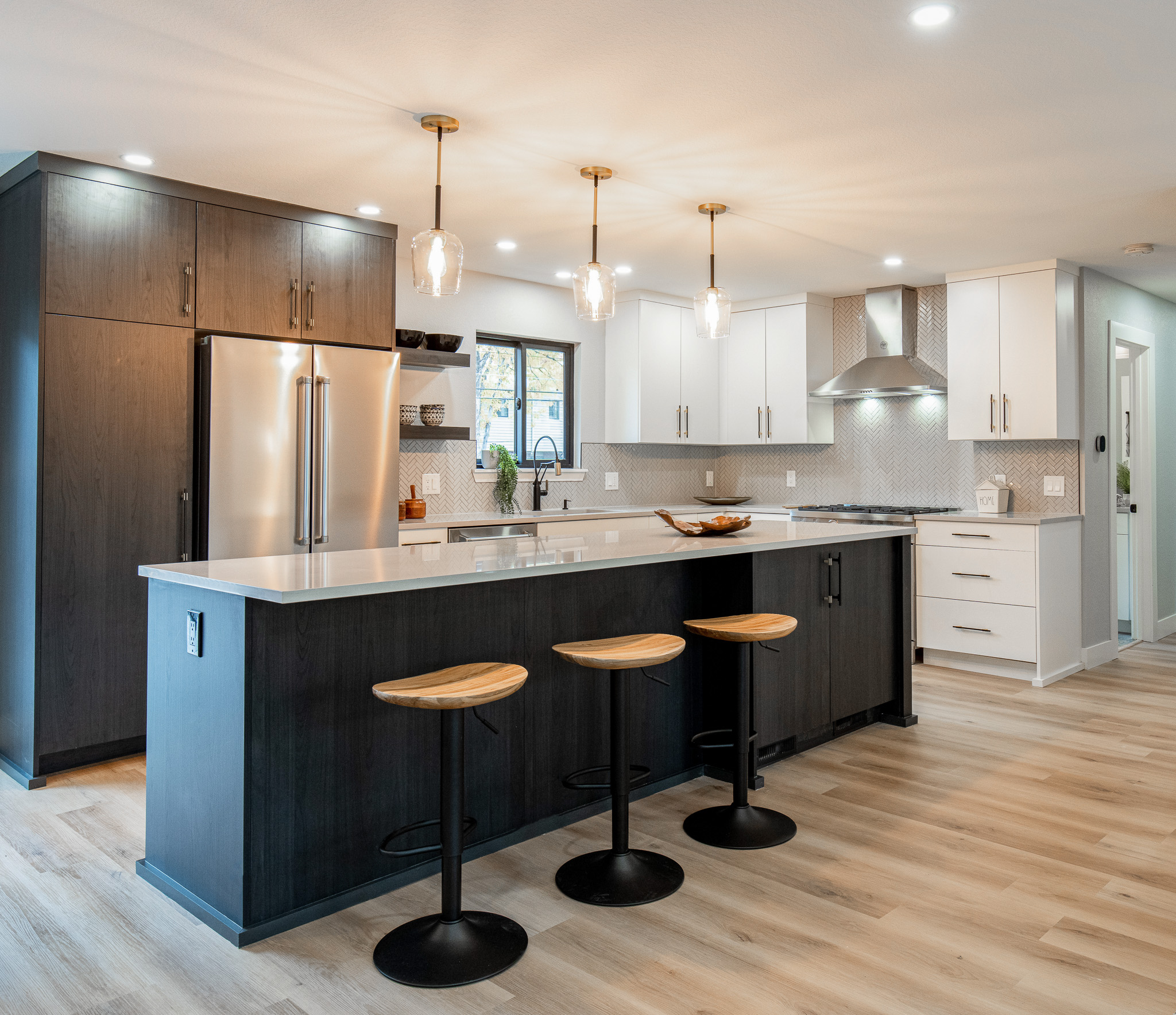 A center island with three barstools stands at the center of a newly renovated kitchen.