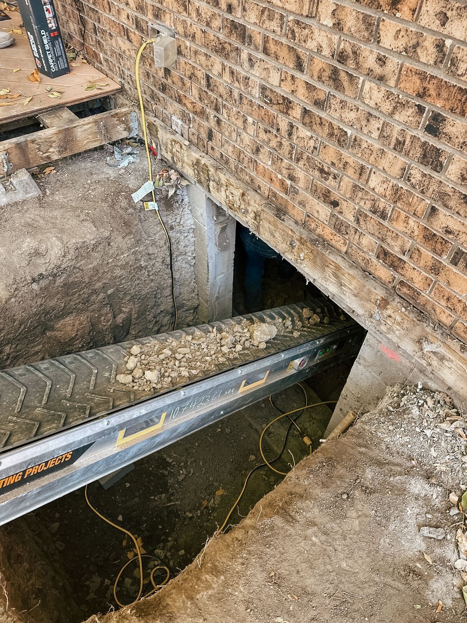 Excavated crawl space dirt exits the access point during a crawl space to basement conversion.